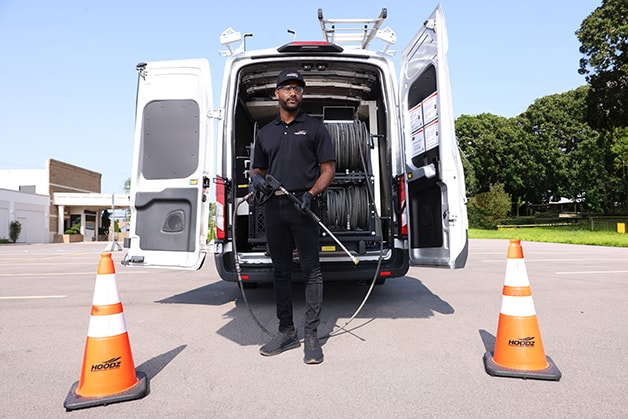 HOODZ technician standing with power washer in front of work van