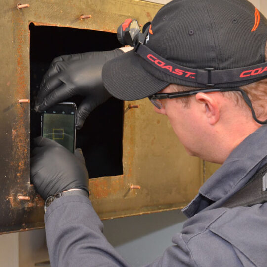 HOODZ tech inspecting an exhaust vent with his phone