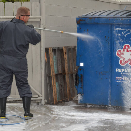 Dumpster pad cleaning with pressure washer